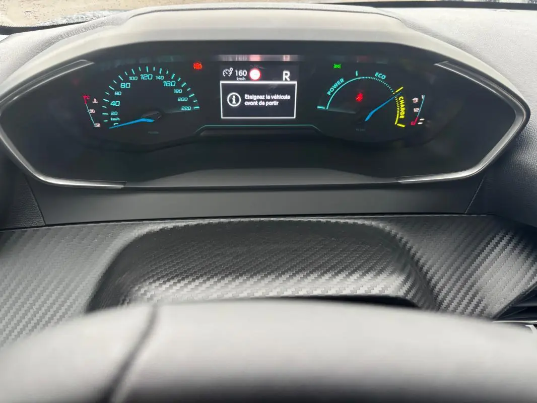 Vue rapprochée du cockpit numérique de la Peugeot 208 gris, affichant la vitesse, mode éco et indicateurs d'énergie.