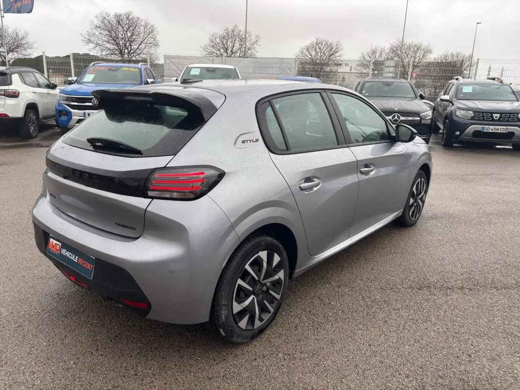 Vue 3/4 arrière droite d'une Peugeot 208 Hybrid grise 2025 avec jantes 16 pouces et badge Style sur le côté.