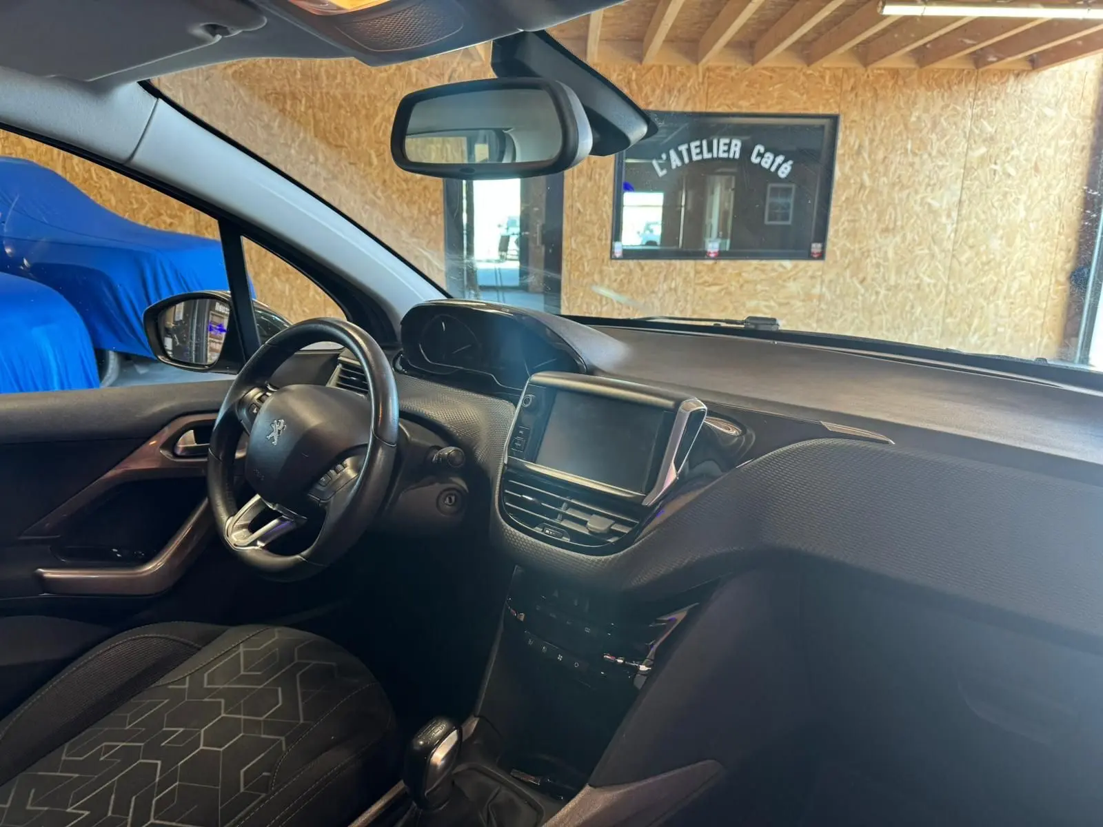 Vue intérieure côté conducteur du Peugeot 2008 gris, mettant en valeur le tableau de bord et l’écran tactile central.
