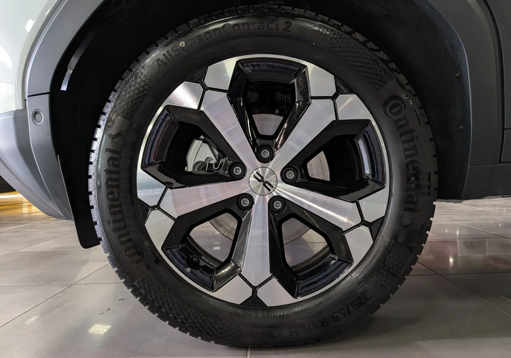 Gros plan sur la roue avant droite du Dacia Duster blanc Glacier, jante alliage bicolore noire et argentée, pneu Continental.
