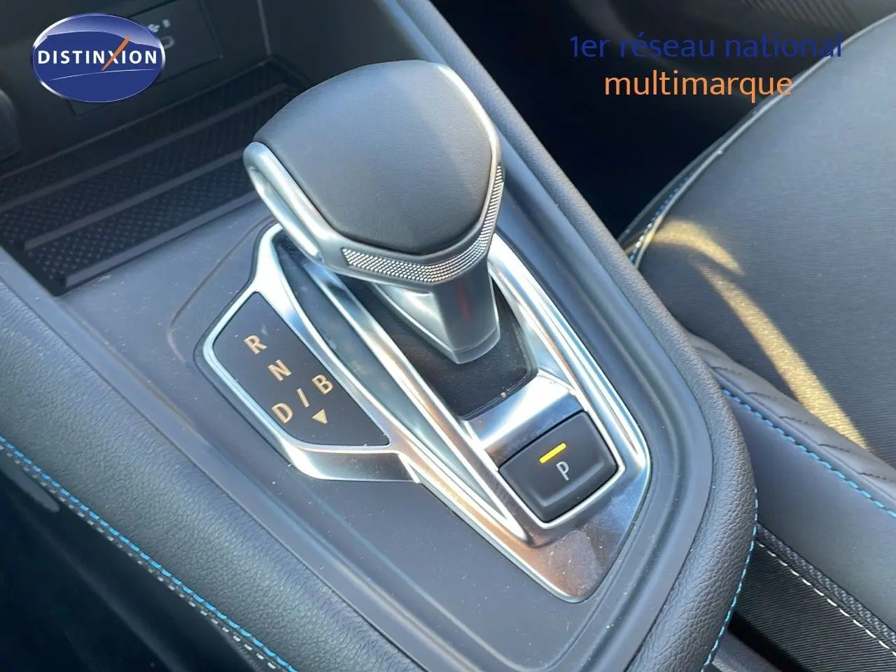 Gros plan sur la commande de boîte automatique du Renault Captur E-Tech hybride, avec cuir noir et surpiqûres bleues.