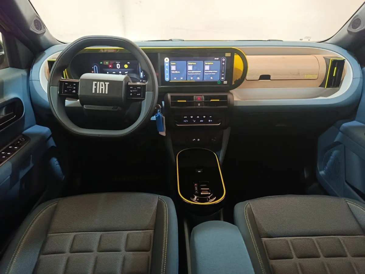 Intérieur avant de la Fiat Grande Panda jaune 2025, tableau de bord moderne avec écran tactile et volant multifonctions.