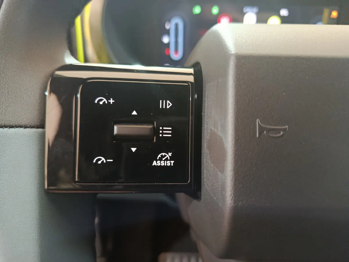 Gros plan sur les commandes de régulateur de vitesse au volant gris de la FIAT Grande Panda jaune.