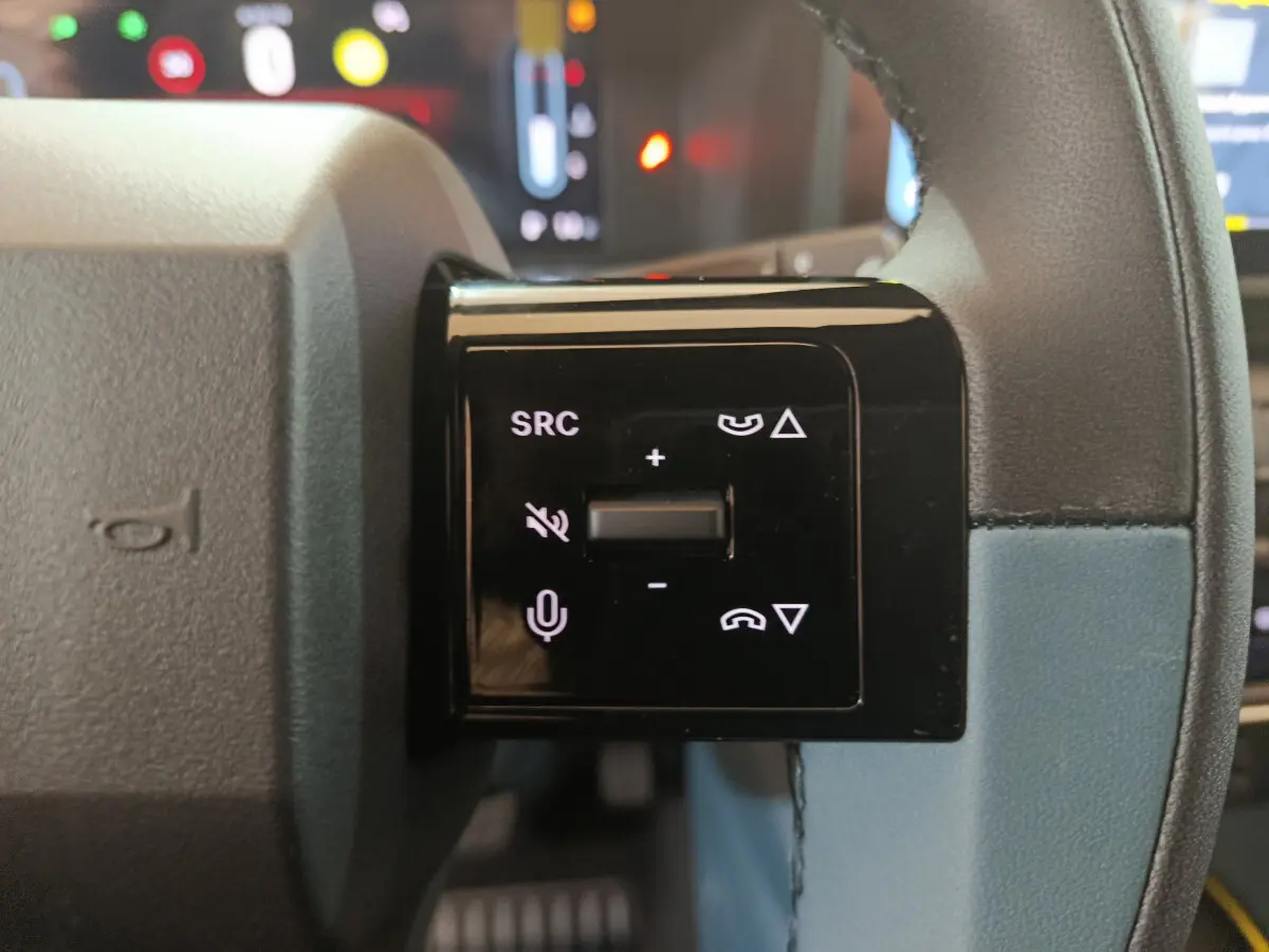 Gros plan sur les commandes vocales et volume au volant cuir bleu de la FIAT Grande Panda jaune 2025.