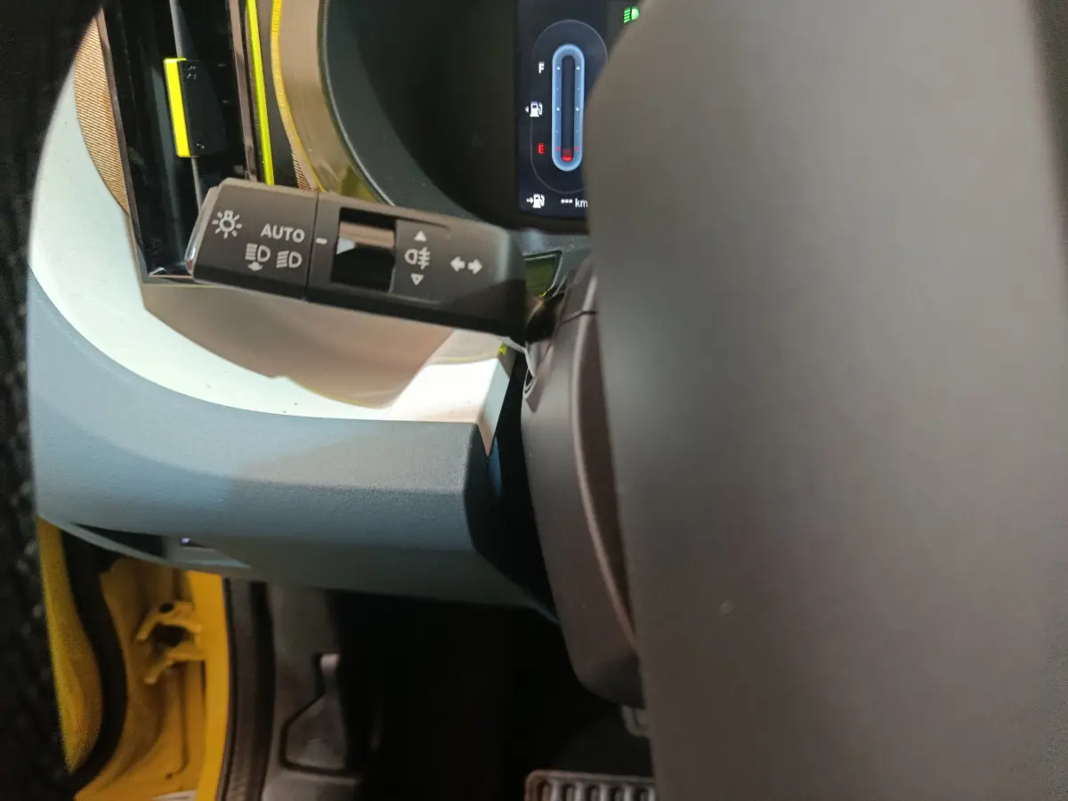 Détail du commodo d'éclairage côté gauche dans l'habitacle jaune vif d'une Fiat Grande Panda 2025.