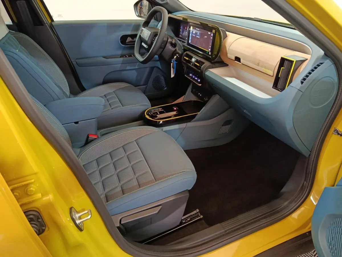 Vue intérieure côté conducteur de la Fiat Grande Panda jaune 2025, avec sièges gris et tableau de bord moderne tactile.