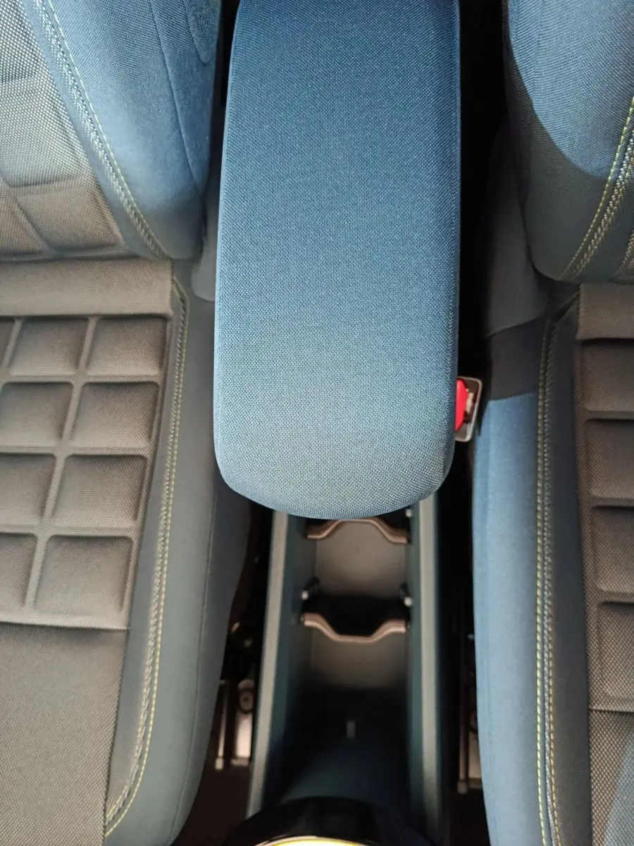 Vue plongeante sur l'accoudoir central bleu et les sièges avant avec surpiqûres jaunes de la Fiat Grande Panda 2025.