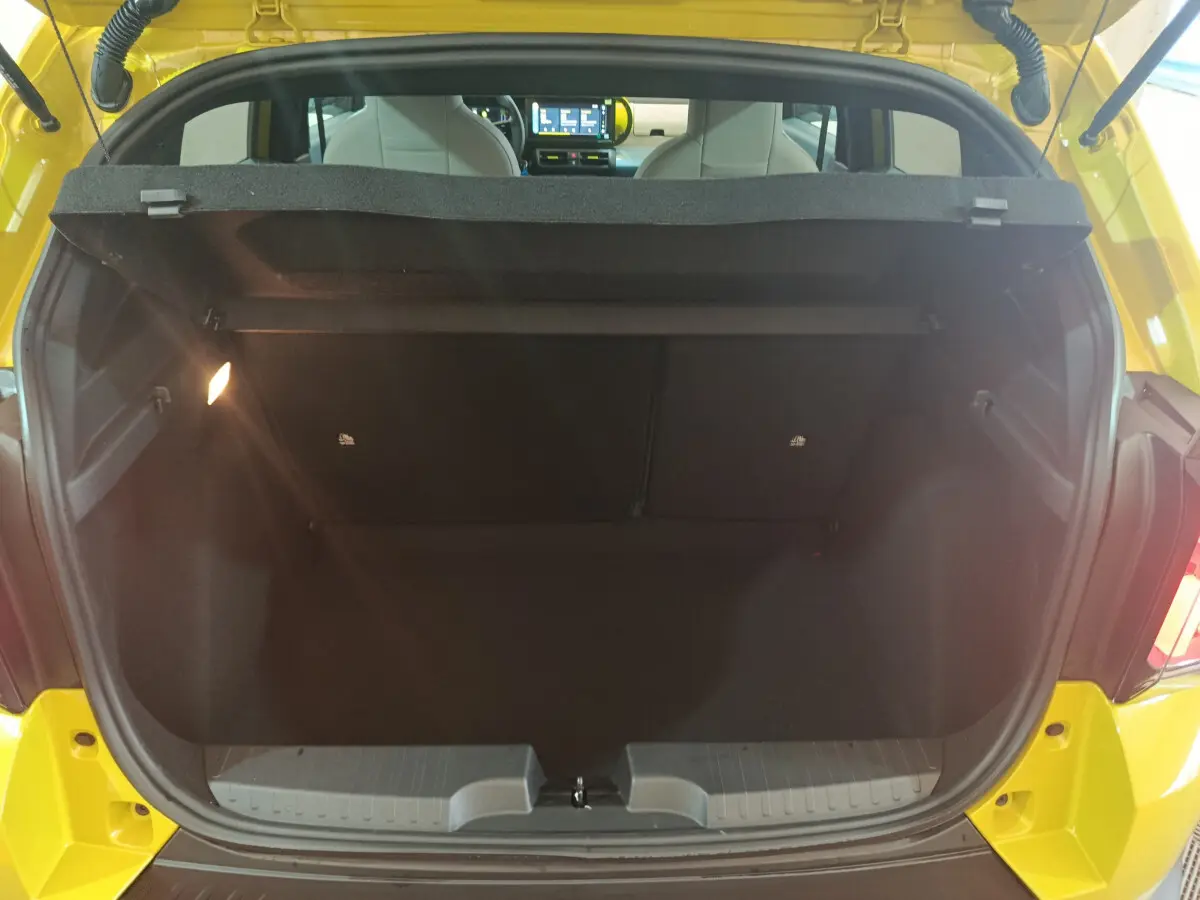 Coffre ouvert d'une FIAT Grande Panda jaune vue arrière, intérieur noir avec tablette de séparation et sièges blancs visibles.