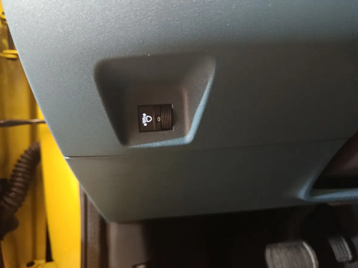 Gros plan sur le réglage d'inclinaison des phares côté conducteur dans une Fiat Grande Panda jaune 2025.