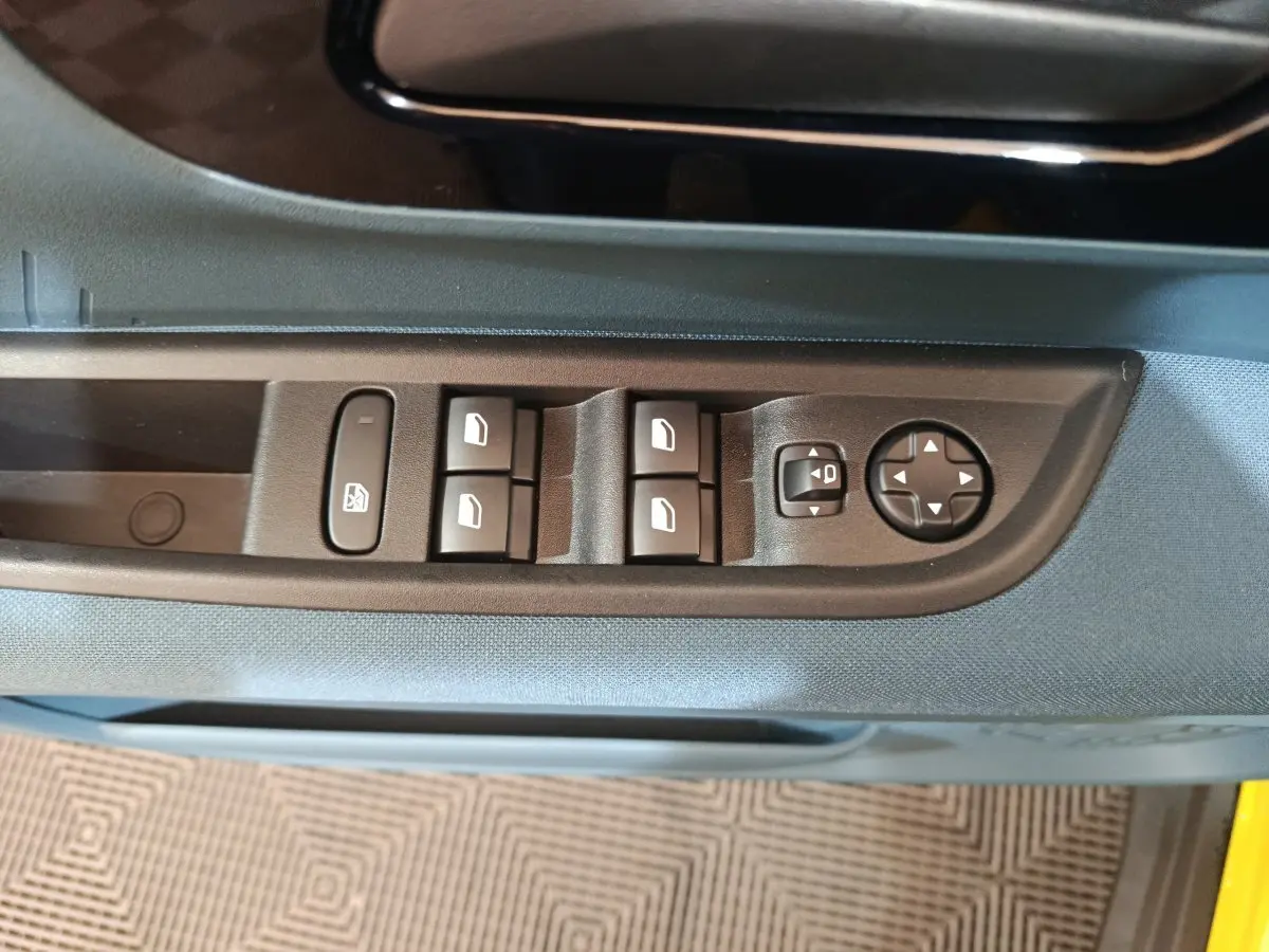 Gros plan sur les commandes des vitres et rétroviseurs côté conducteur de la FIAT Grande Panda jaune 2025.