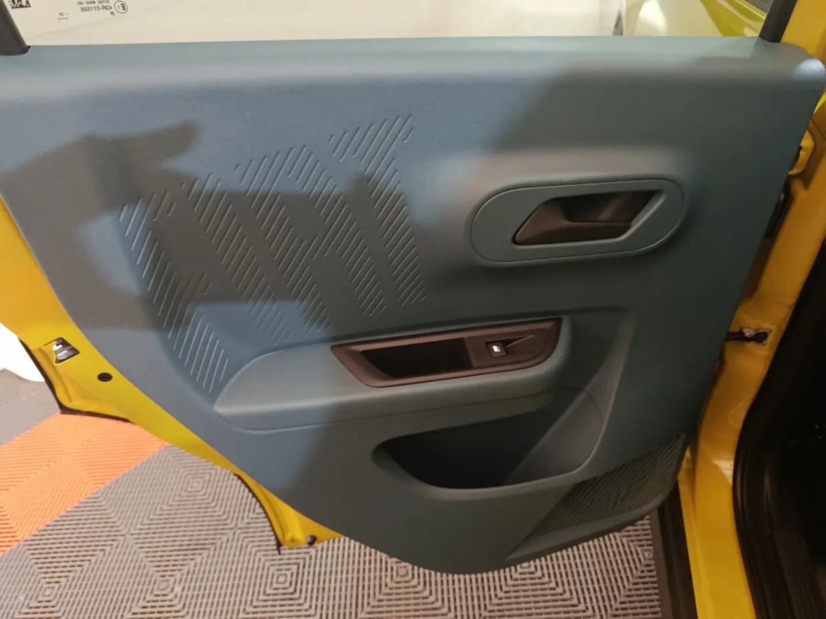 Vue intérieure de la porte avant gauche bleue avec poignée et bouton de verrouillage, cadre jaune visible FIAT Grande Panda 2025.