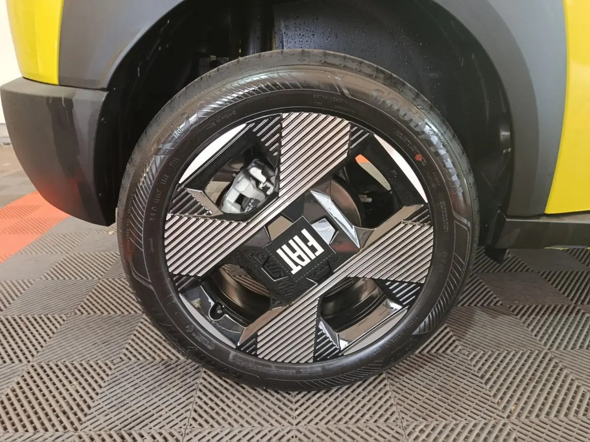 Gros plan sur la roue avant gauche de la FIAT Grande Panda jaune, mettant en valeur la jante noire et argentée au design géométrique.