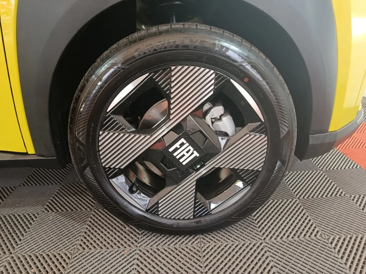 Gros plan sur la roue avant gauche jaune de la Fiat Grande Panda avec jante noire et grise au logo FIAT central.