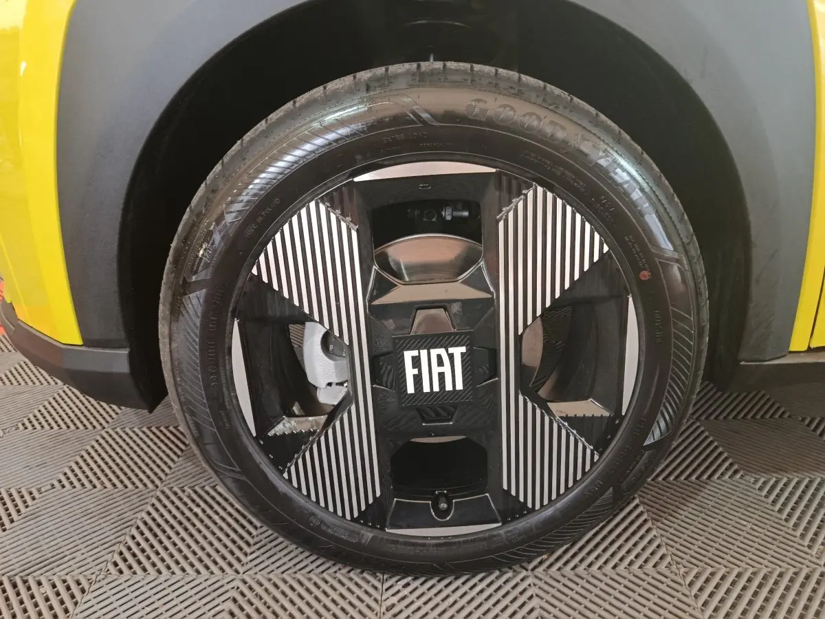 Gros plan sur la roue avant droite noire et argentée avec logo FIAT, partie basse jaune de la Fiat Grande Panda visible.