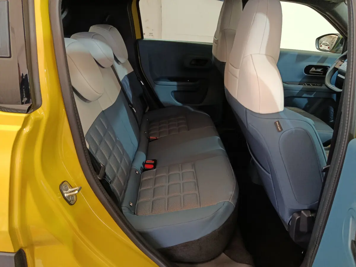Vue intérieure arrière côté gauche de la Fiat Grande Panda jaune, montrant la banquette bi-ton bleu et beige.