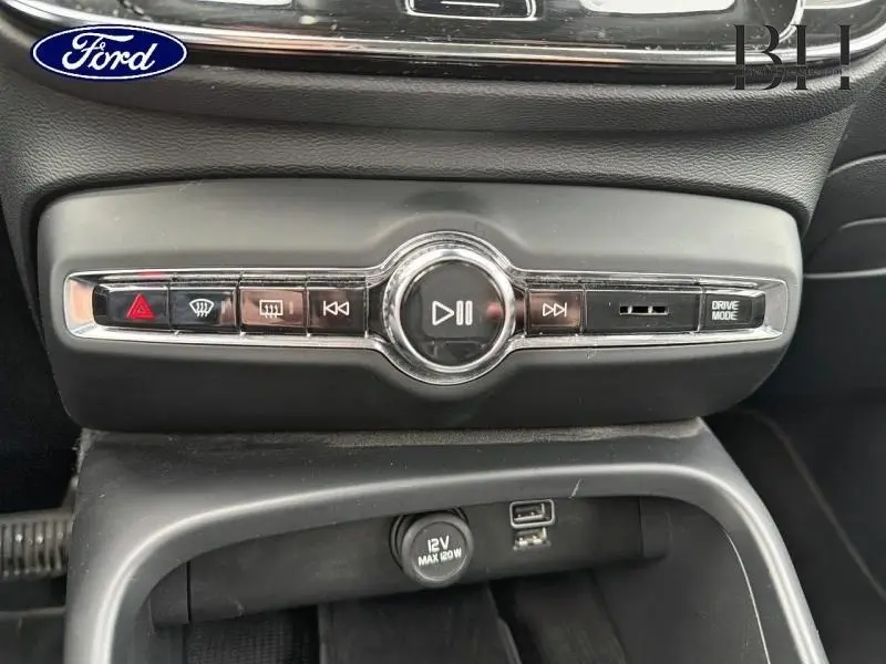 Vue rapprochée de la console centrale noire du Volvo XC40 blanc, avec commandes audio et bouton Drive Mode.