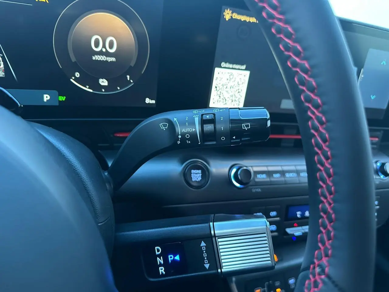 Gros plan sur le tableau de bord du Hyundai Kona 2025, volant cuir noir avec surpiqûres rouges et commandes digitales.