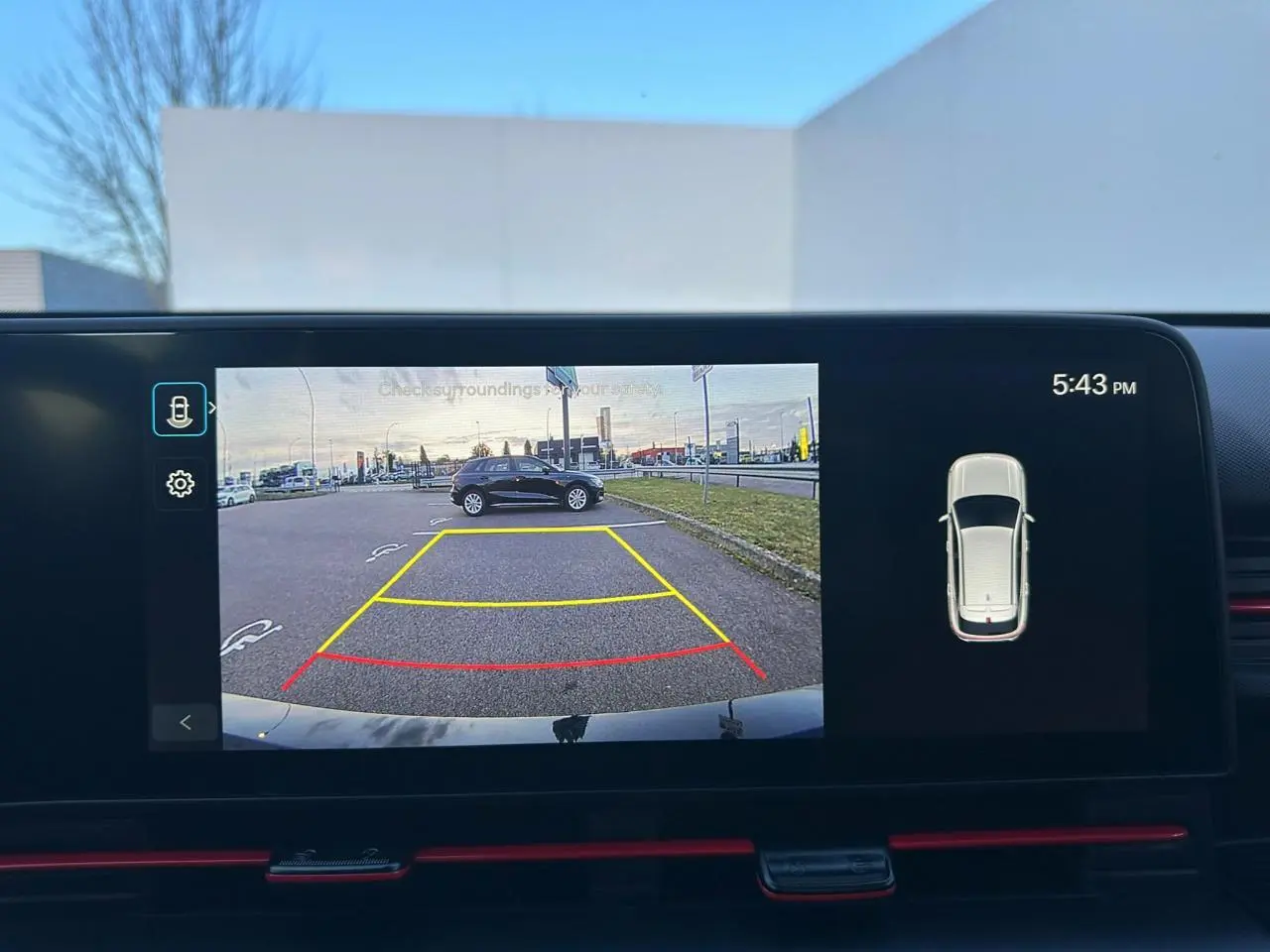 Vue écran caméra de recul montrant un Hyundai Kona noir Abyss Metal en stationnement sur un parking extérieur.