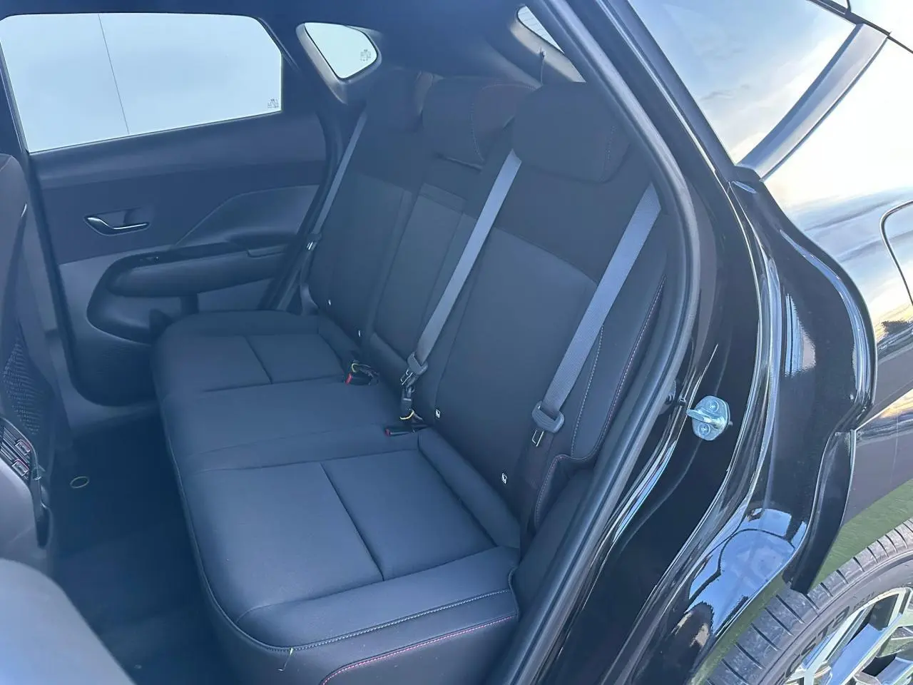 Vue intérieure sur la banquette arrière noire du Hyundai Kona II 2025, avec portières ouvertes côté droit.