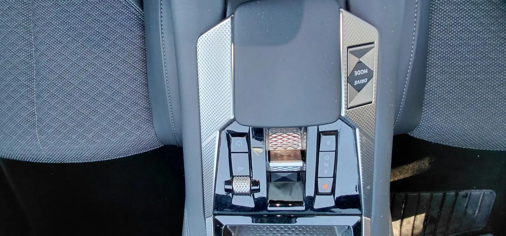 Gros plan sur la console centrale du DS4 hybride gris 2024, avec commandes de boîte automatique et bouton Drive Mode.