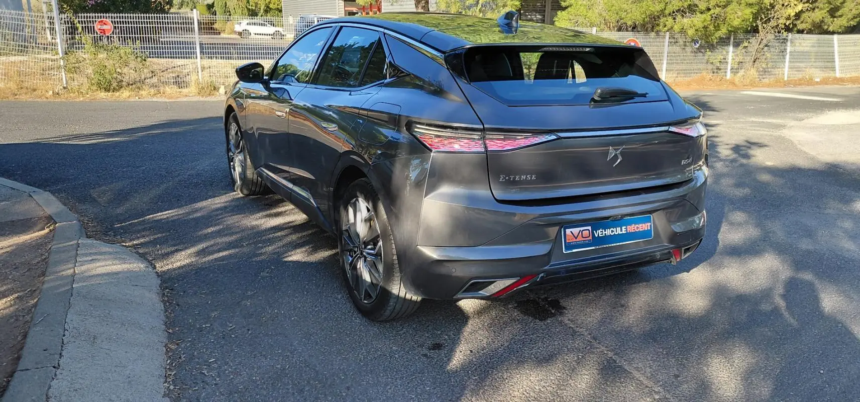 Vue 3/4 arrière droite d'une DS4 hybride E-Tense gris métallisé avec jantes alliage 19 pouces, sur route ensoleillée.