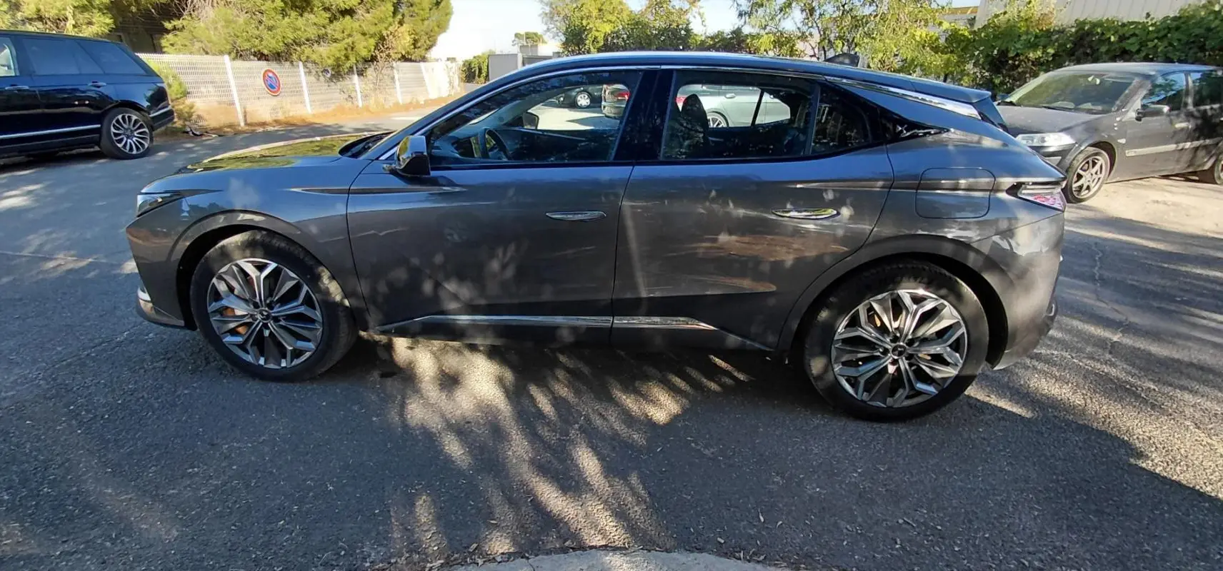 Vue latérale côté gauche d'une DS4 hybride E-Tense 225 gris métallisé avec jantes alliage 19 pouces, en extérieur.