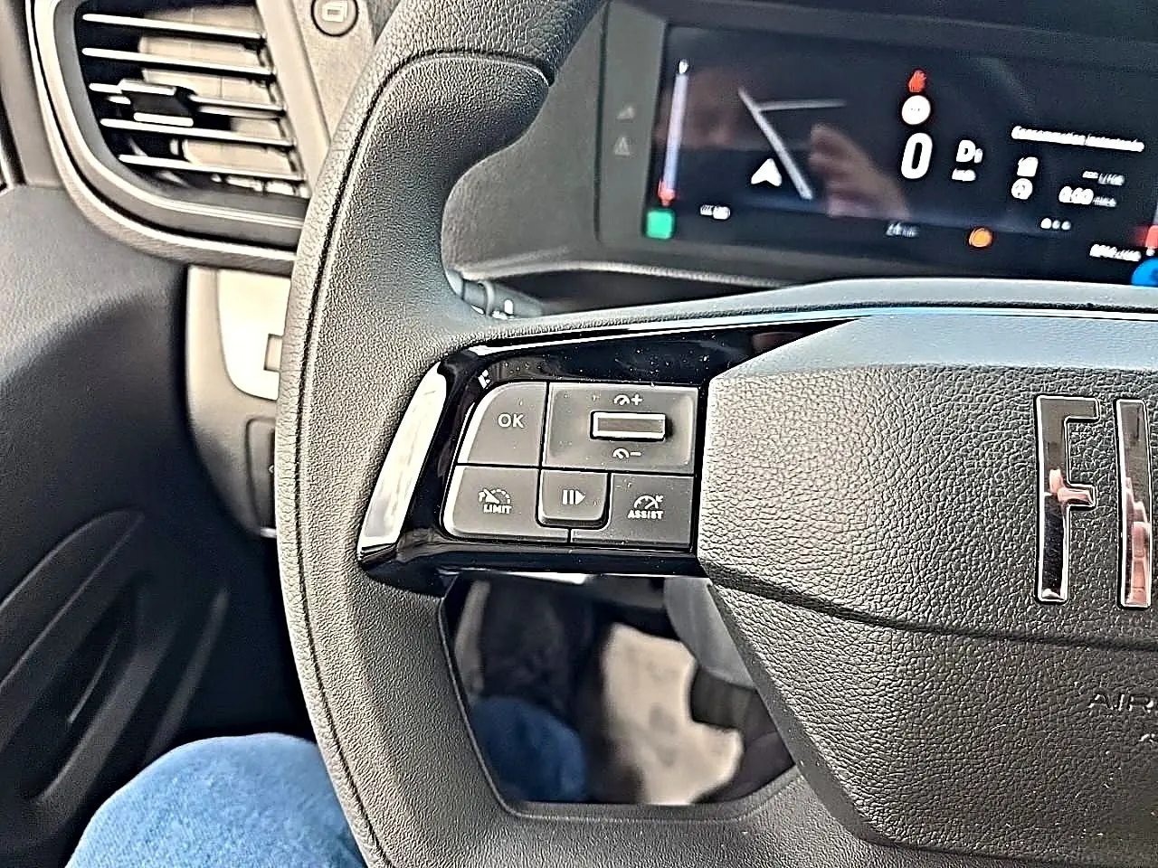 Gros plan sur le volant noir du Fiat Scudo Combi avec commandes multifonctions à gauche et tableau de bord numérique.
