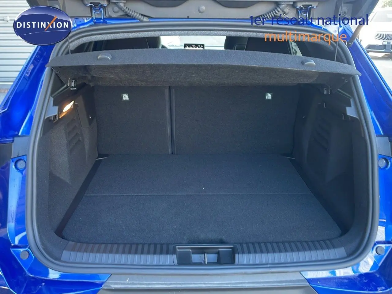 Coffre ouvert vu de l'arrière du Renault SYMBIOZ bleu iron metal, montrant un espace de chargement spacieux et propre.