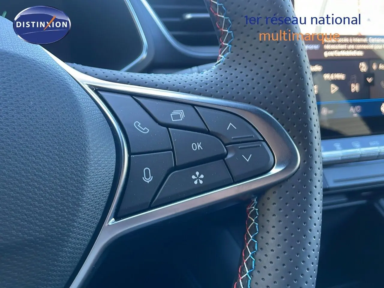 Gros plan sur les commandes du volant en cuir noir perforé avec surpiqûres tricolores du Renault Symbioz E-Tech Hybrid 2025.