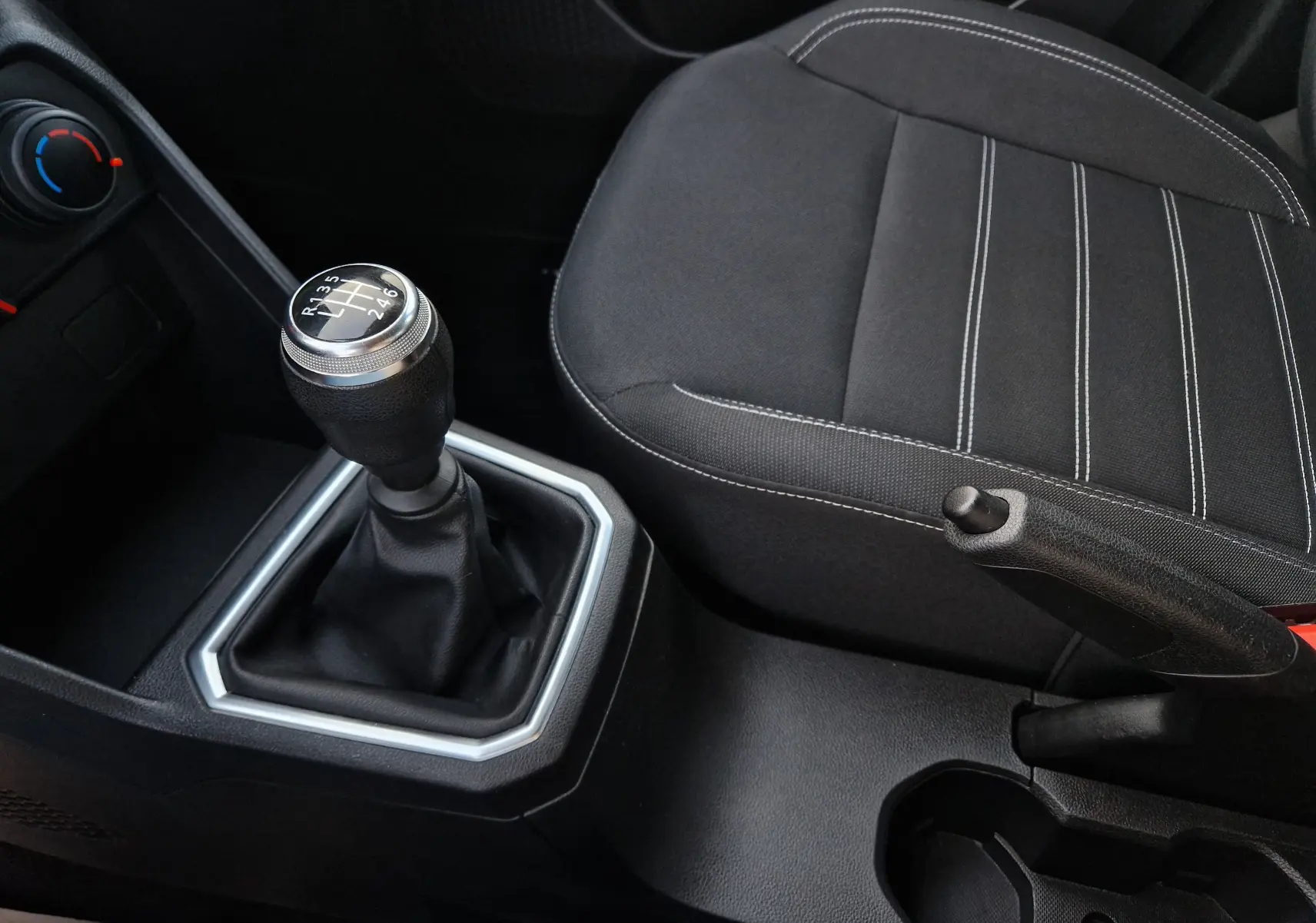 Vue rapprochée de la console centrale de la Dacia Sandero blanche 2022, avec levier de vitesse manuel et siège tissu noir.