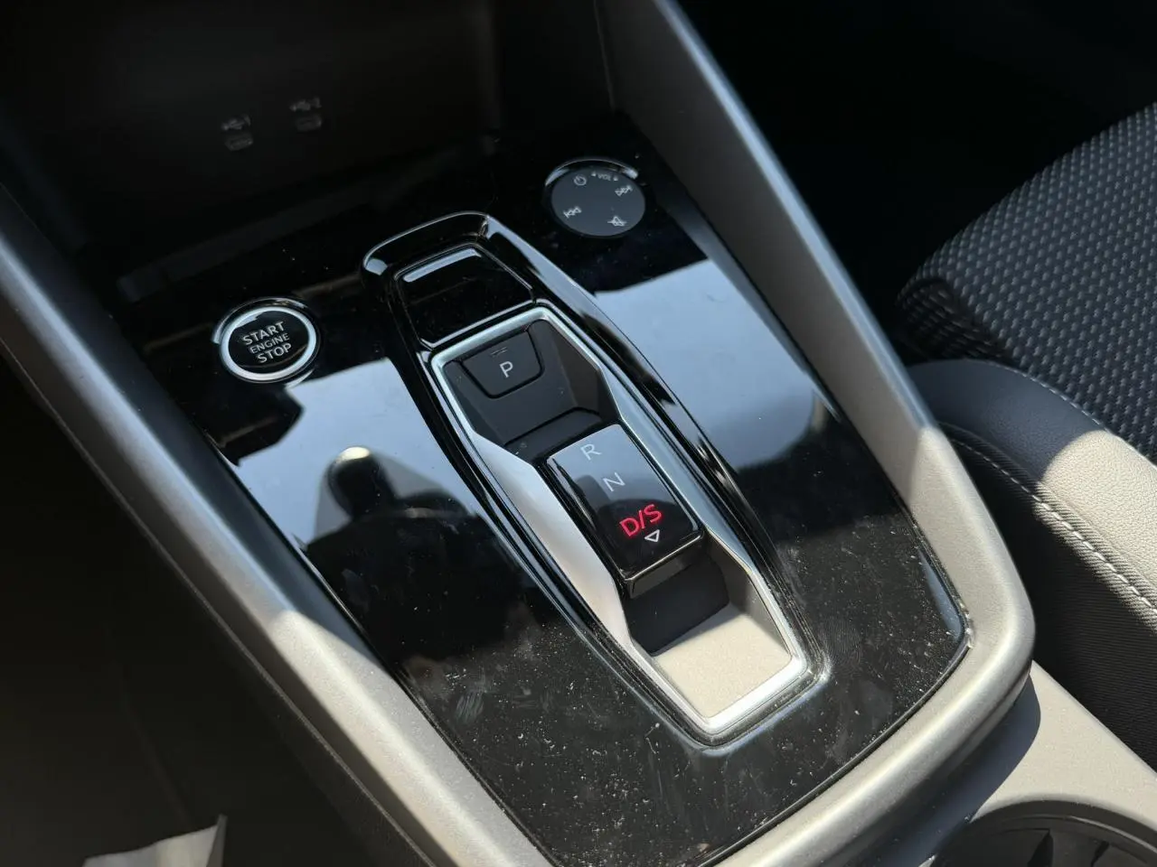 Gros plan sur la console centrale noire brillante avec levier de vitesses automatique et bouton start/stop de l'Audi A3 Sportback 2025.