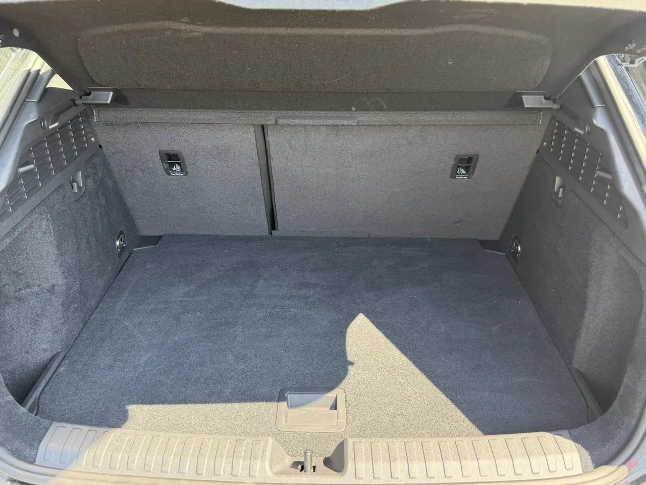 Coffre ouvert vu de l'arrière d'une Audi A3 Sportback noir Mythe, espace de chargement propre et vide.
