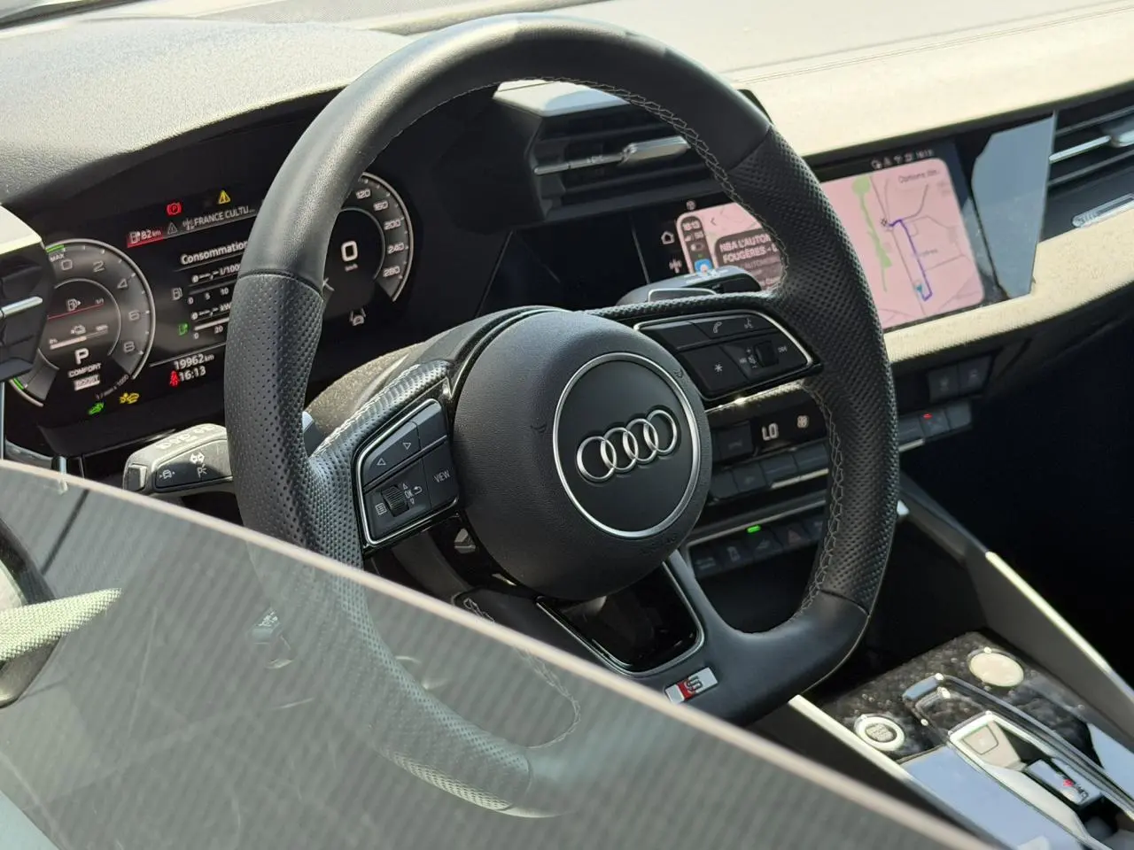 Vue rapprochée du volant cuir perforé avec logo Audi et tableau de bord numérique de l'Audi A3 Sportback 2025.