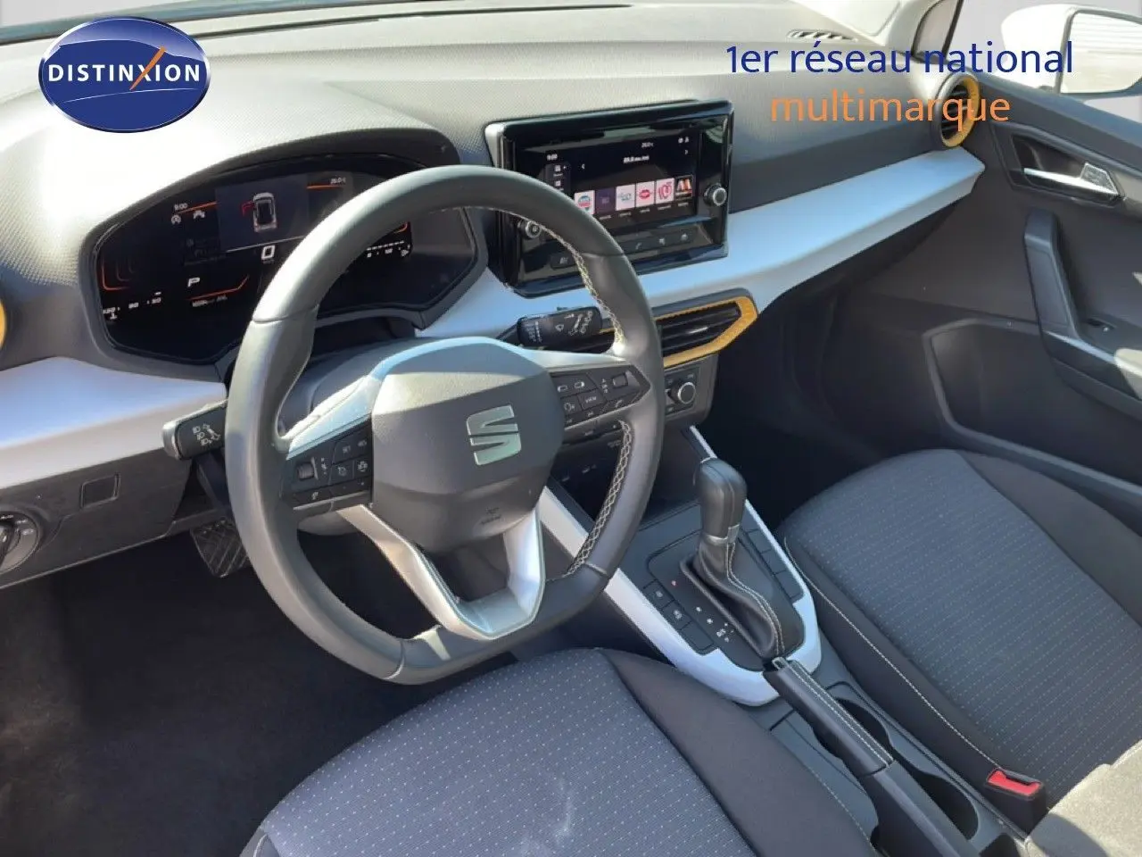 Vue intérieure côté conducteur du tableau de bord et console centrale du SEAT Arona blanc métal avec volant cuir et écran tactile.