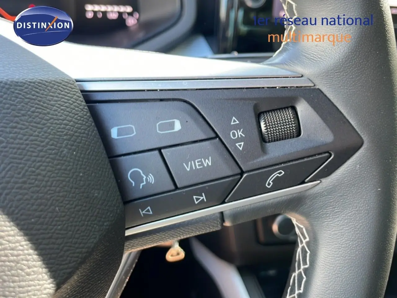 Gros plan sur les commandes au volant côté gauche du SEAT Arona 2025, volant cuir noir avec boutons multifonctions.