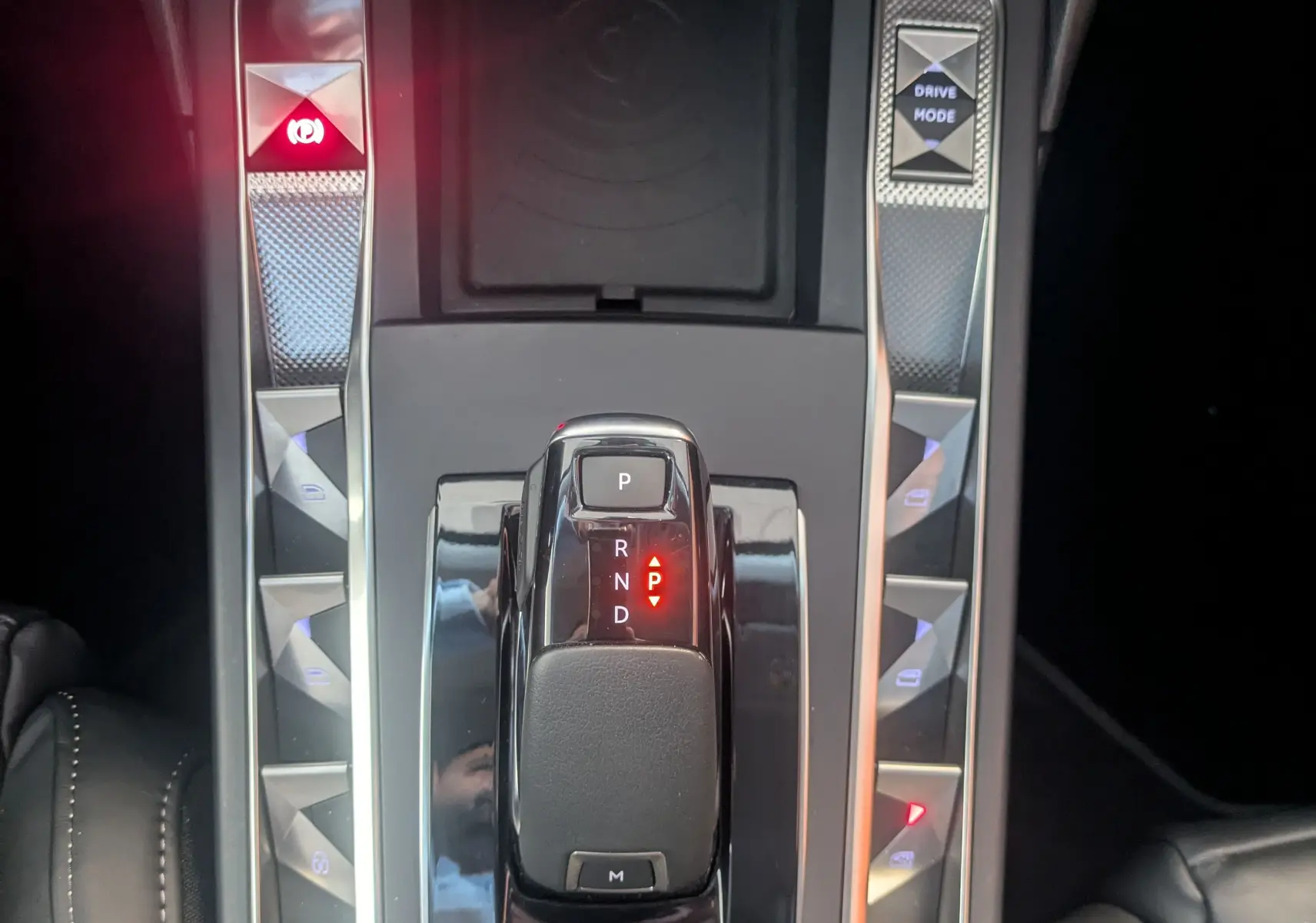 Vue plongeante sur la console centrale noire du DS3 2024 avec levier de vitesses automatique et boutons lumineux argentés.