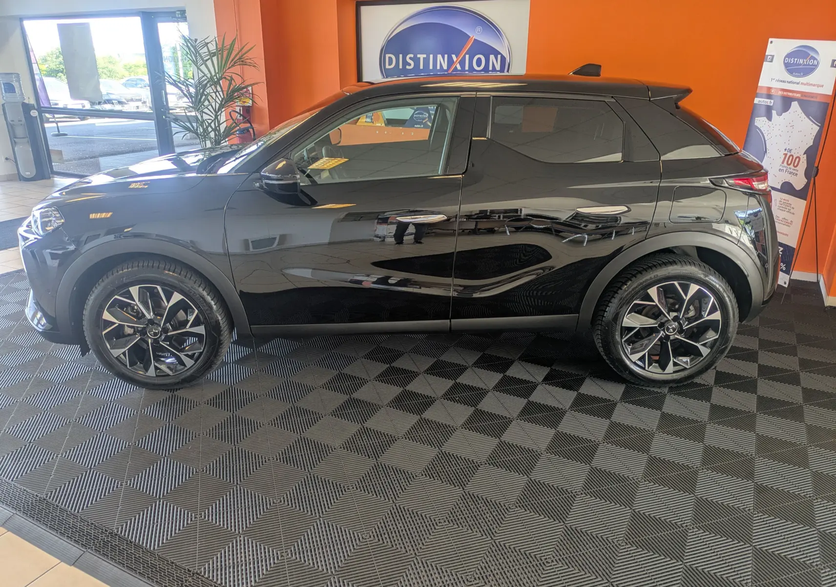Vue de profil côté gauche d'un DS3 noir 2024 avec jantes alliage bicolores et toit noir brillant en showroom.
