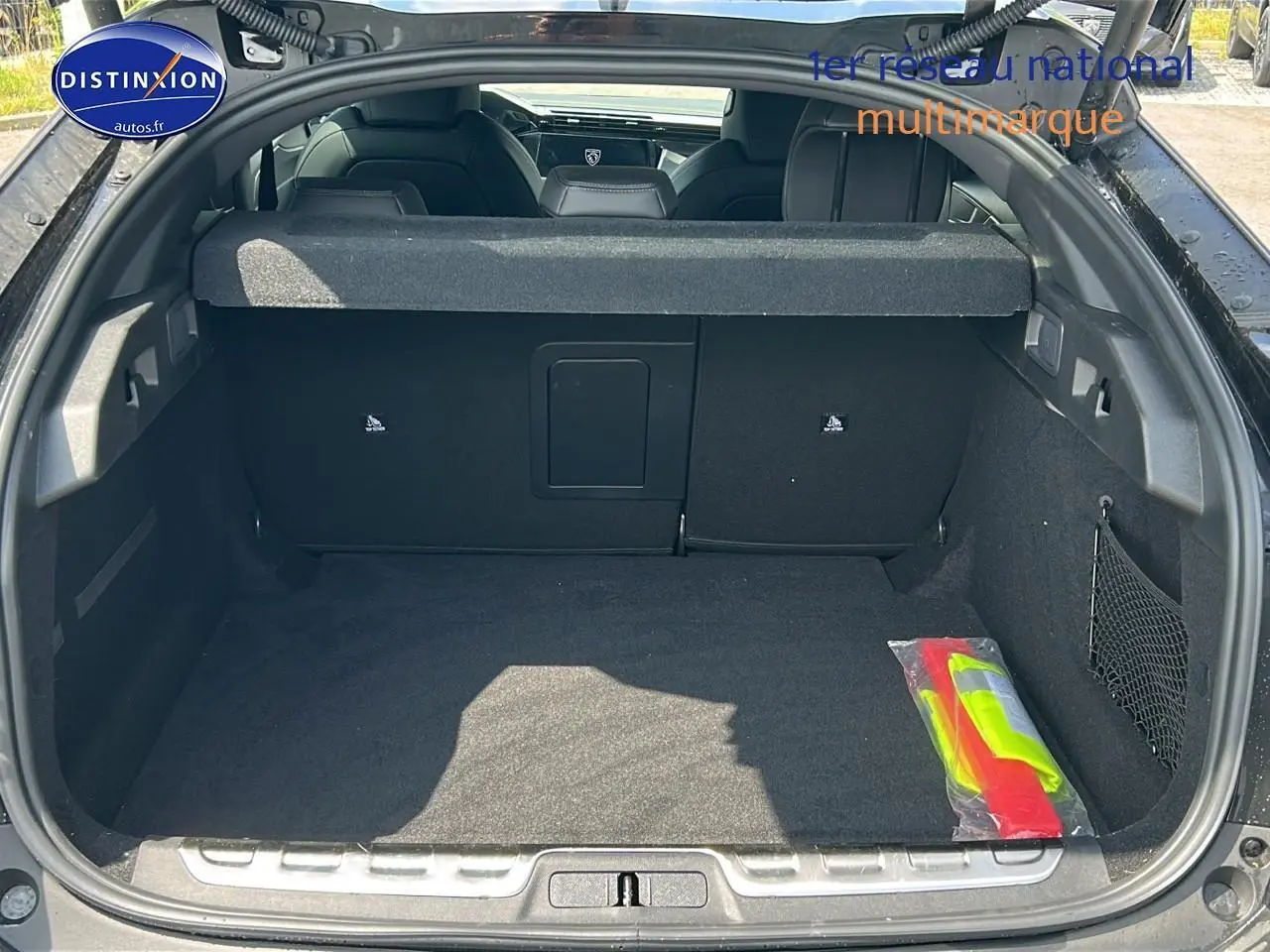 Coffre ouvert d'une Peugeot 408 Hybrid 145 GT noir, vue arrière montrant l'espace de chargement et la banquette arrière.
