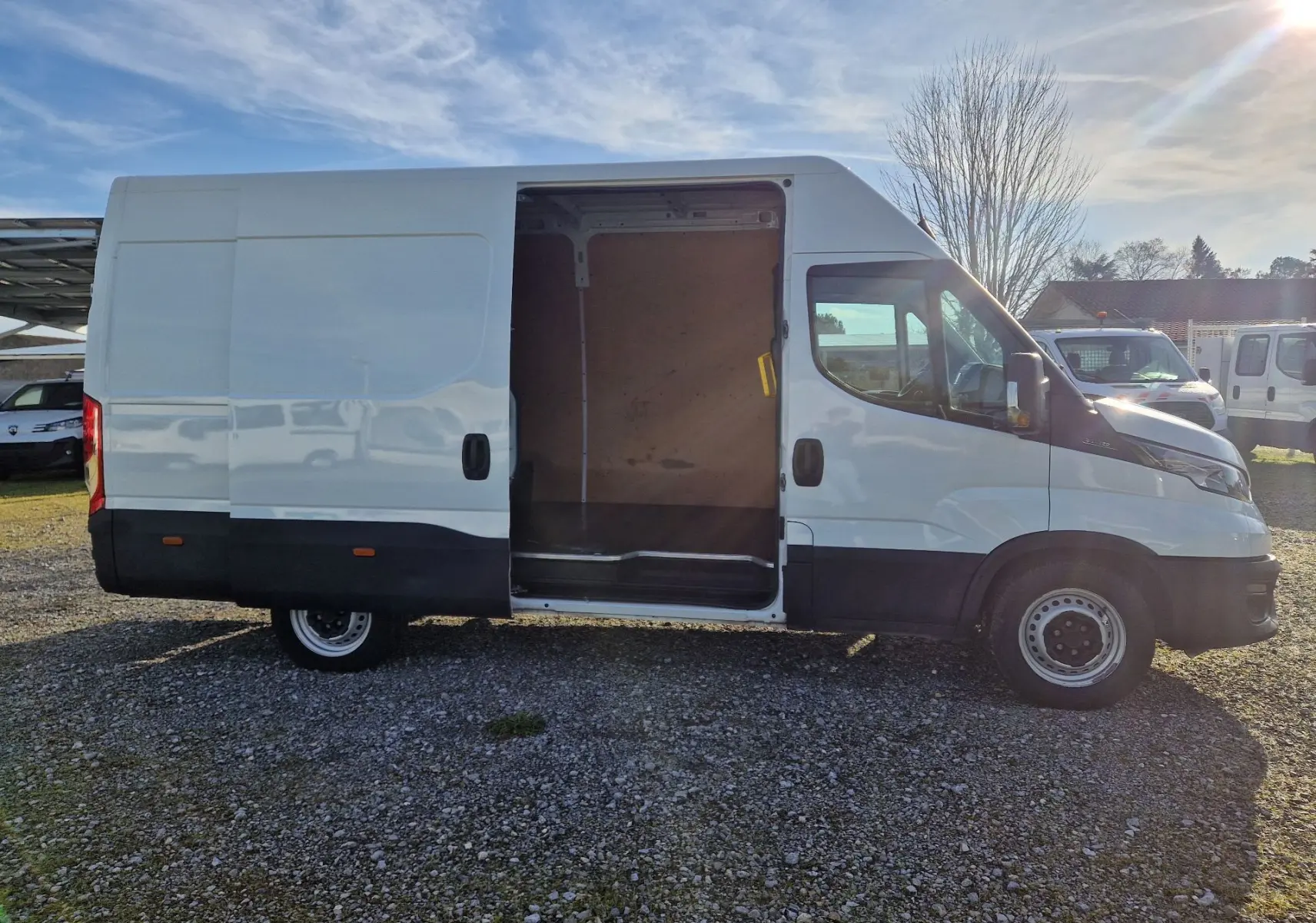 Vue latérale droite d’un Iveco Daily Fourgon blanc 2023 avec porte coulissante ouverte montrant l’intérieur vide.