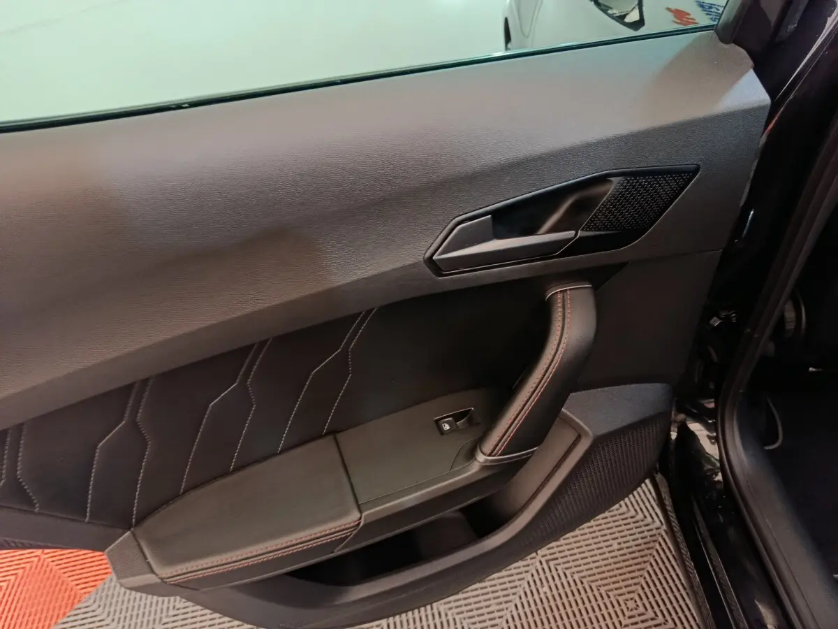 Gros plan sur la porte avant gauche noire du CUPRA Formentor 2024 avec surpiqûres rouges et poignée intégrée.