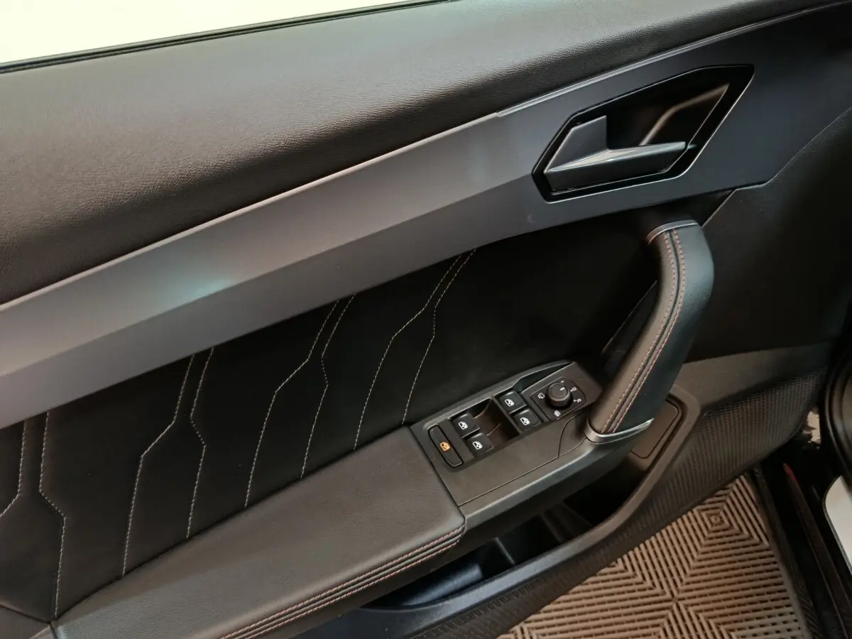 Gros plan sur la porte intérieure côté conducteur du CUPRA Formentor noir, avec surpiqûres et commandes électriques.