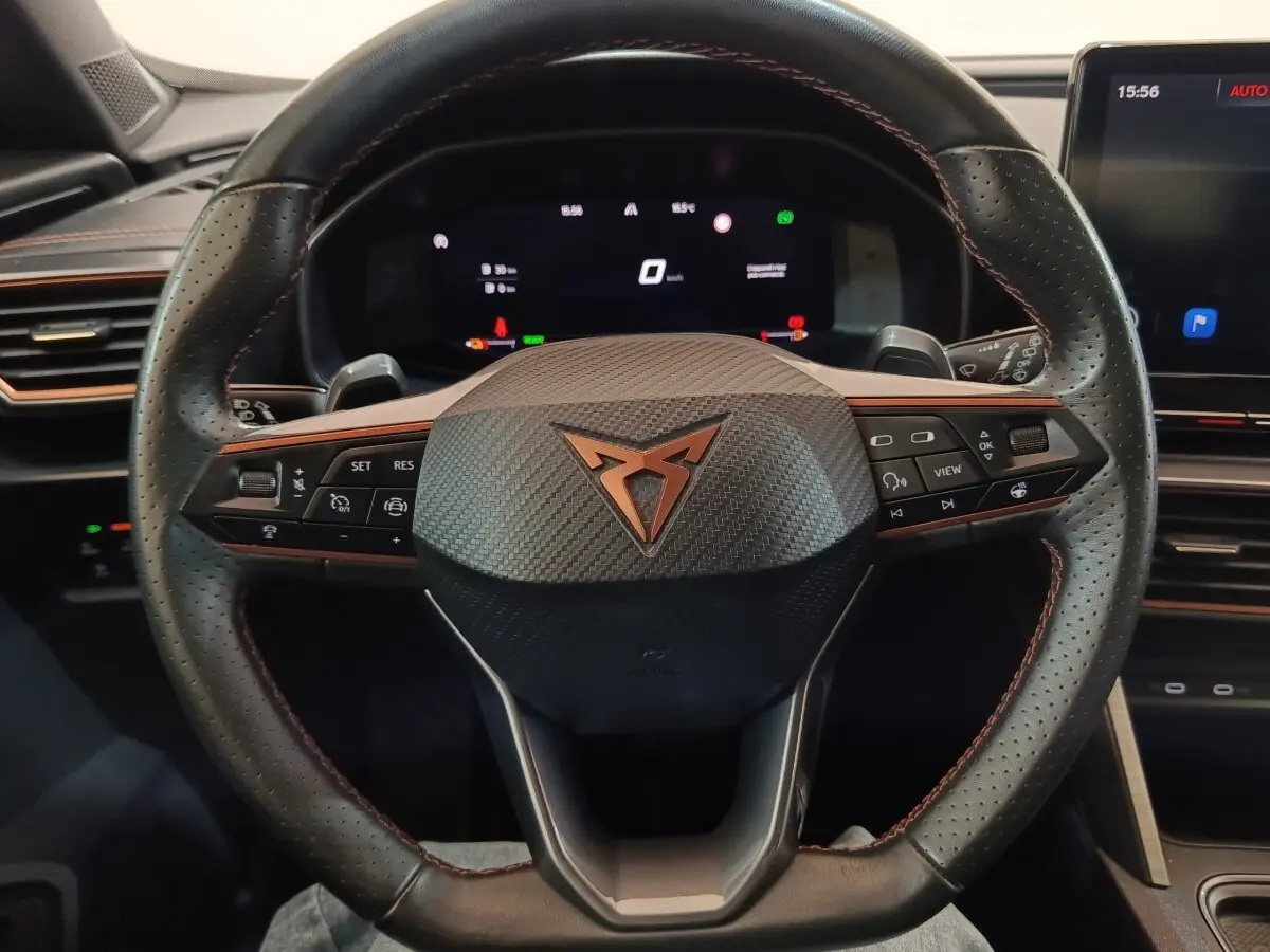 Vue rapprochée du volant noir perforé avec logo Cupra cuivré et tableau de bord numérique du Formentor 2024.