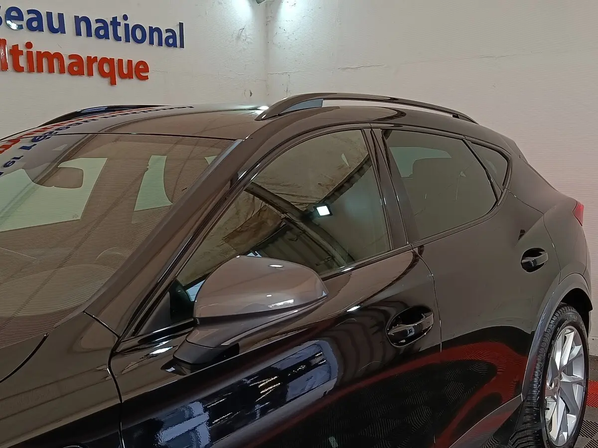 Vue de côté gauche rapprochée du CUPRA Formentor noir 2024 avec rétroviseur ton caisse et rails de toit visibles.