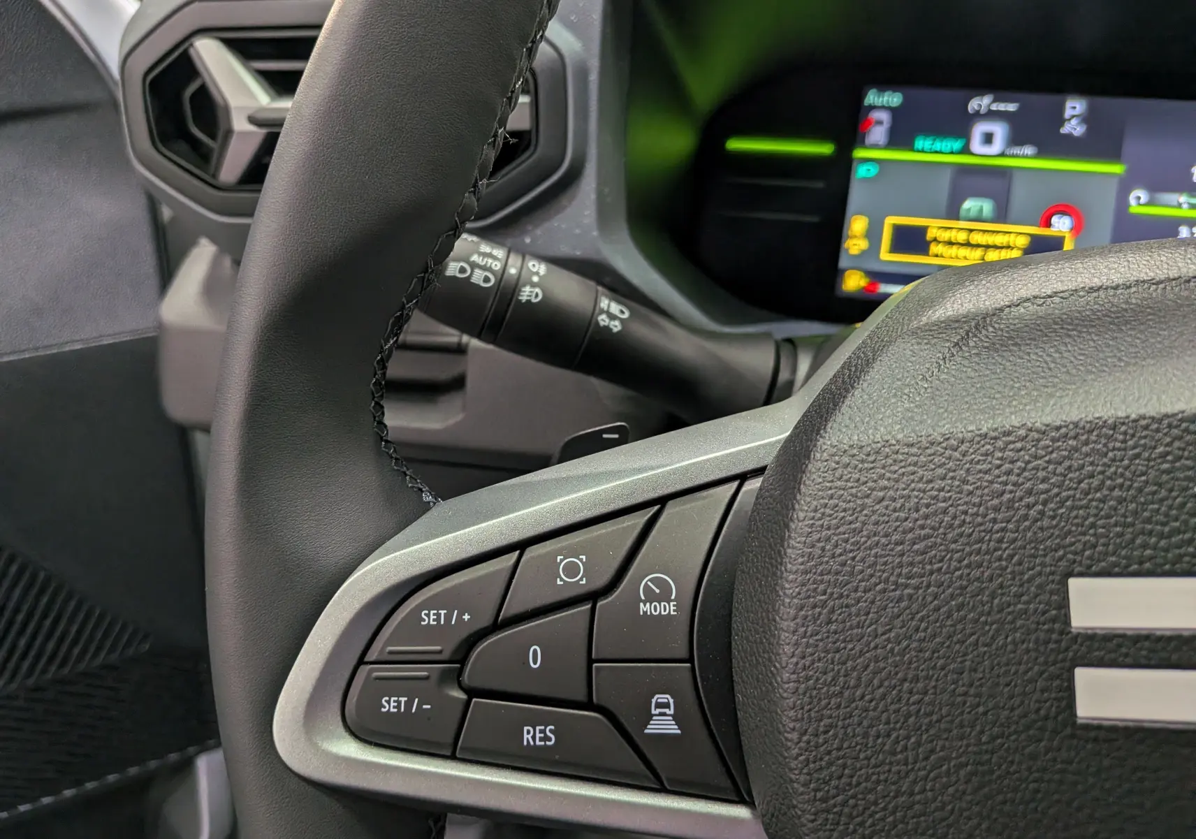 Gros plan sur le volant noir du Dacia Duster Hybrid-G 150 CH 4x4 2026 avec commandes de régulateur et tableau de bord numérique.