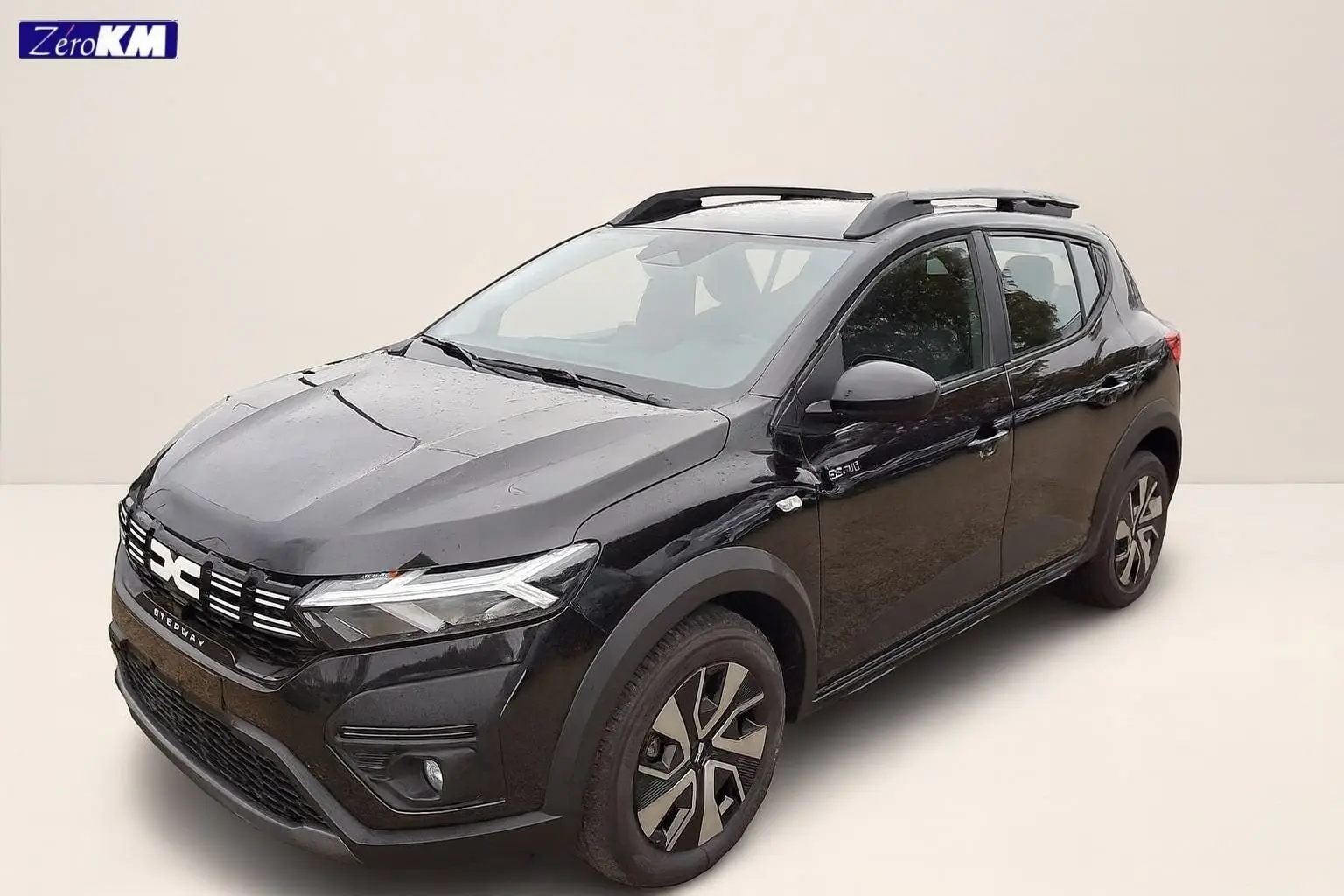 Vue 3/4 avant droite d'une Dacia Sandero Stepway noire nacrée avec barres de toit et jantes 16 pouces.