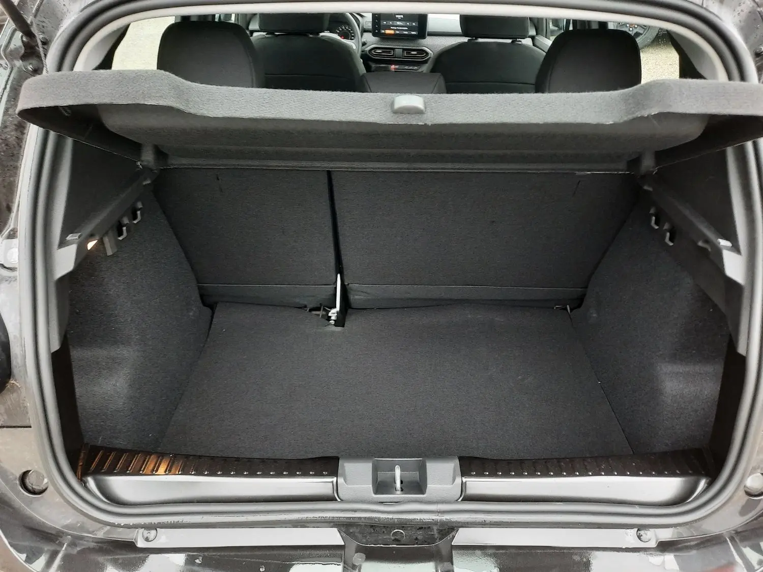 Coffre ouvert vue arrière d'une Dacia Sandero Stepway noir nacré, intérieur tissu gris et banquette rabattable.