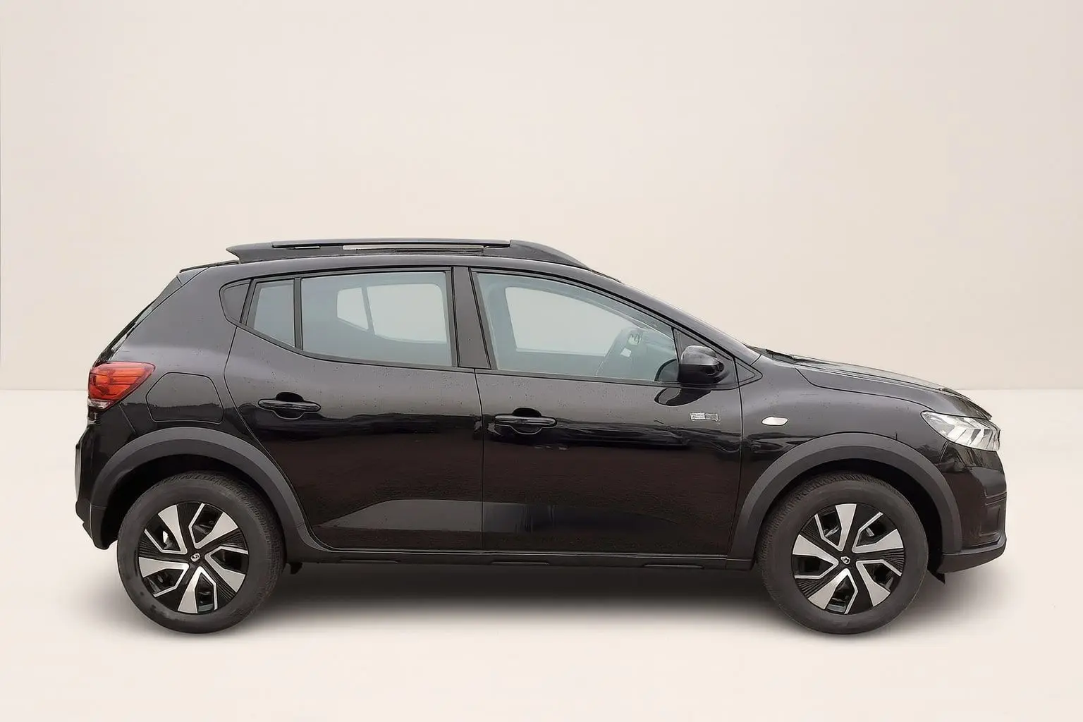 Profil droit de la Dacia Sandero Stepway 2025 noir nacré avec barres de toit et jantes 16 pouces à enjoliveurs.
