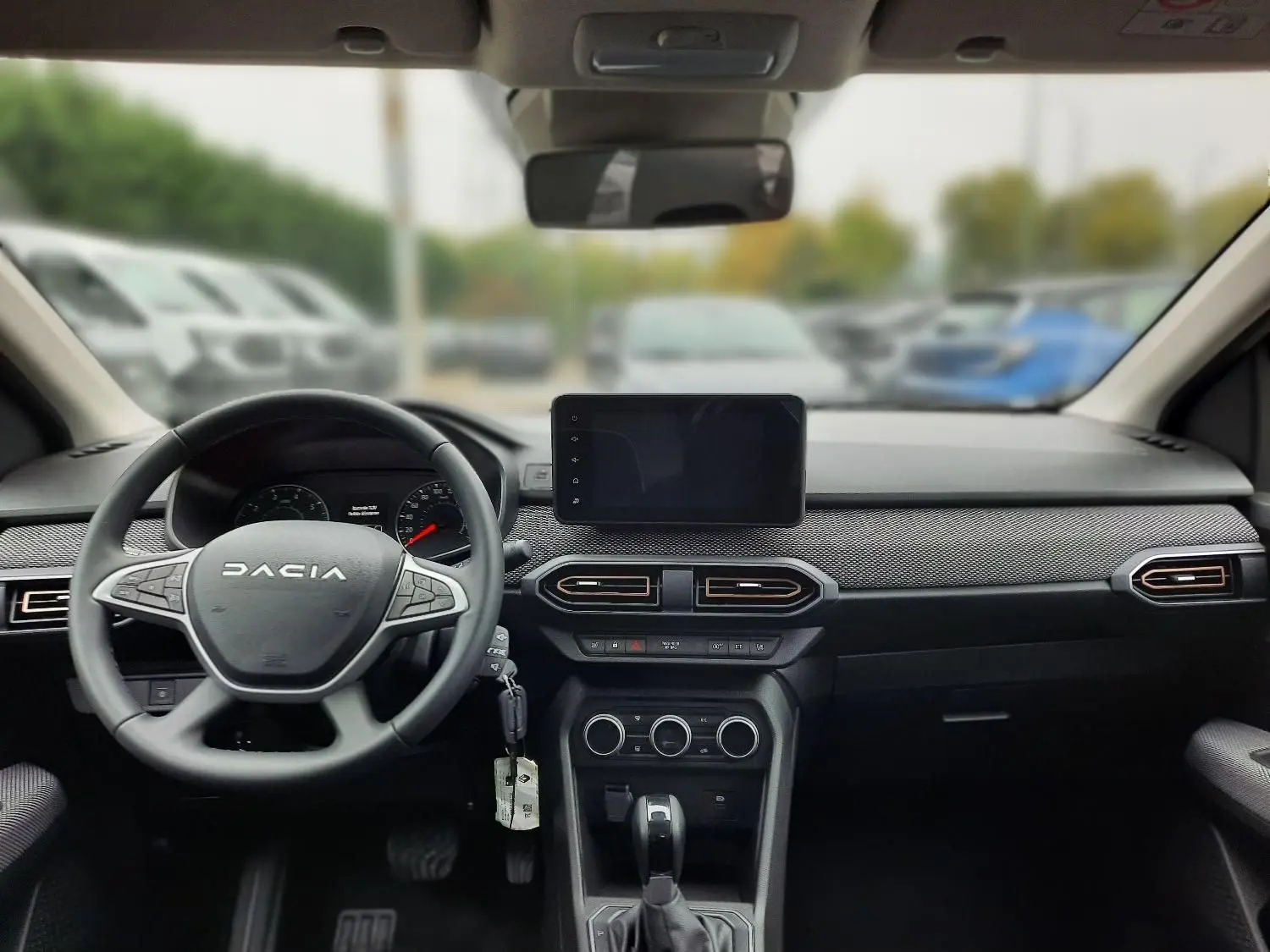 Vue intérieure avant du tableau de bord noir de la Dacia Sandero Stepway 2025 avec volant multifonctions et écran tactile central.