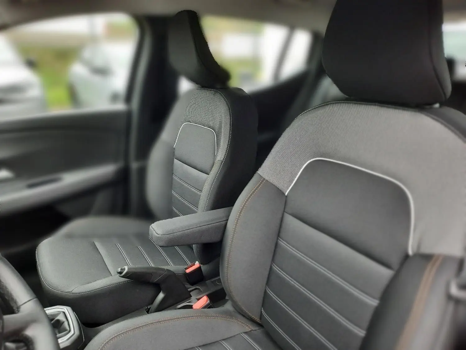 Gros plan sur les sièges avant gris avec accoudoir central dans l'habitacle d'une Dacia Sandero Stepway 2025.