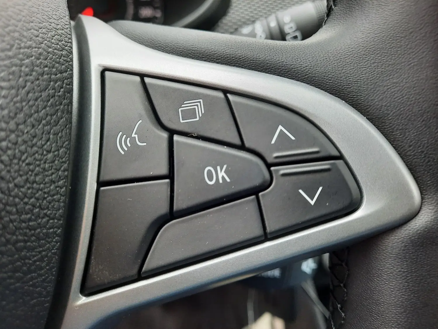 Gros plan sur les commandes multifonctions noires du volant cuir de la Dacia Sandero Stepway 2025.